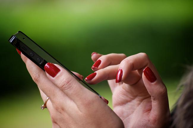 En person som håller en mobiltelefon i sin hand och trycker på tangenterna.