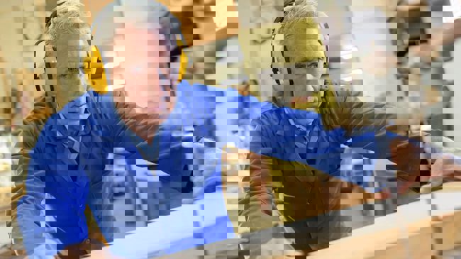 Äldre man som sågar på en bordssåg